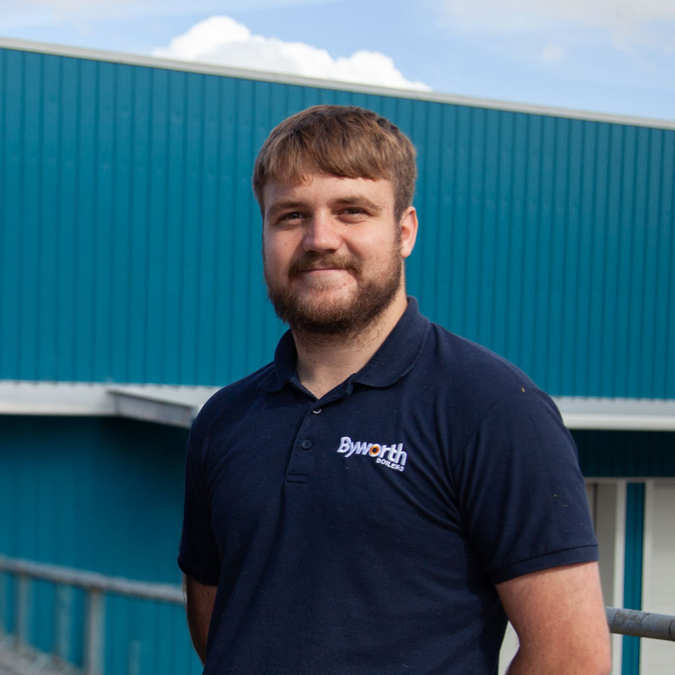 Man with a beard stood smiling in front of a blue building 